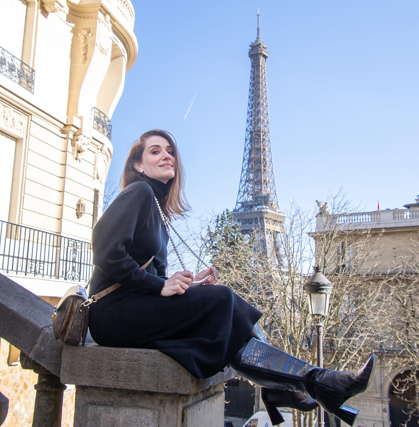Woman sitting on a ledge with the Eiffel Tower in the background